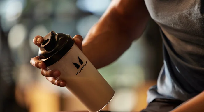 Un athlète Myprotein qui secoue un shaker de protéines avec de la créatine.