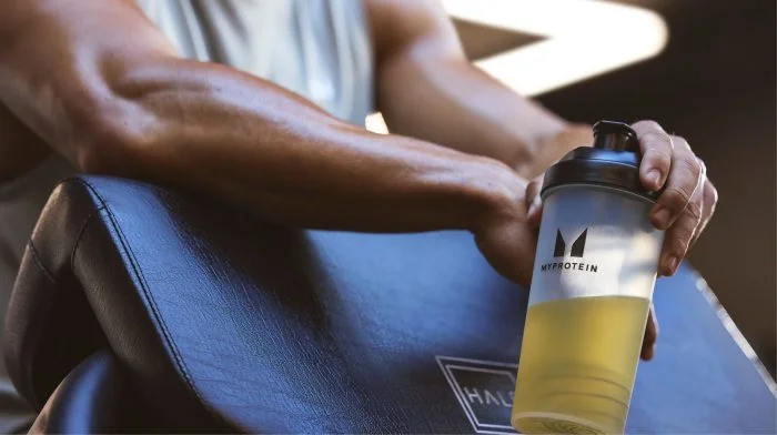 Une personne se détendant après un entraînement avec un shaker de complément.
